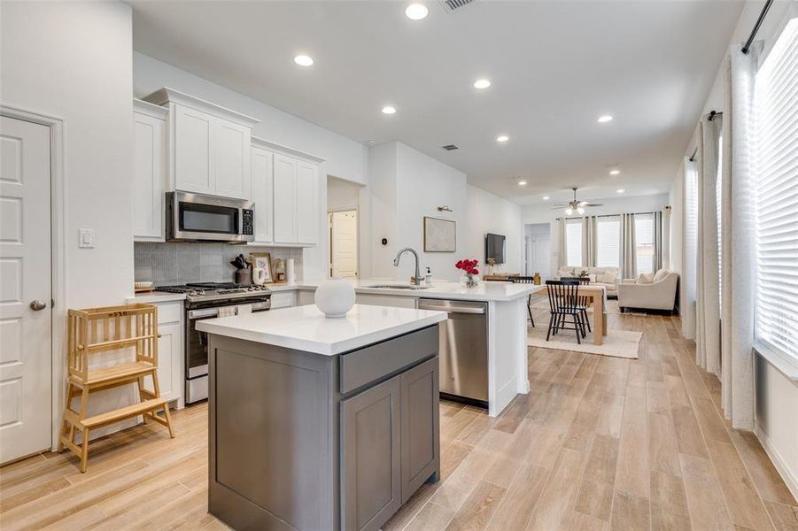 Kitchen featuring white cabinetry, open floor plan, recessed lighting, a kitchen island, and tasteful backsplash