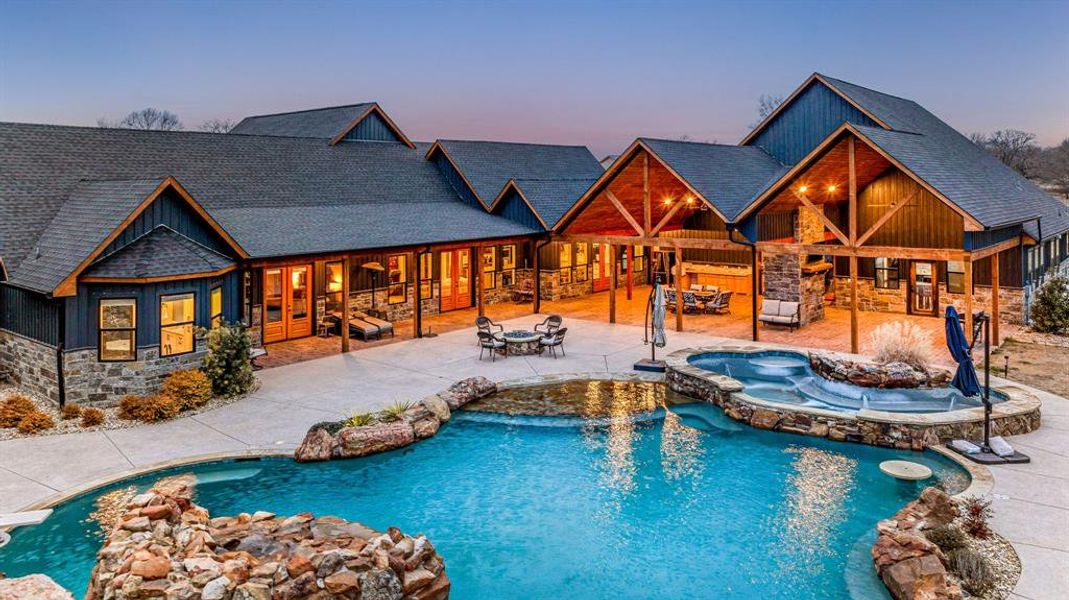 Pool at dusk with a patio, a pool with connected hot tub, and an outdoor fire pit