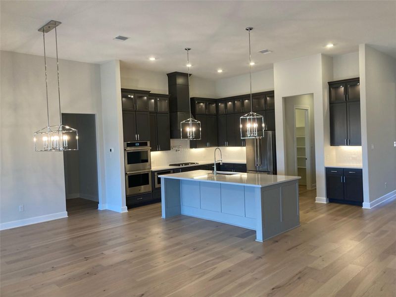 The kitchen has a sprawling center island with undermount stainless steel sink, push button garbage disposal, and Moen faucets.