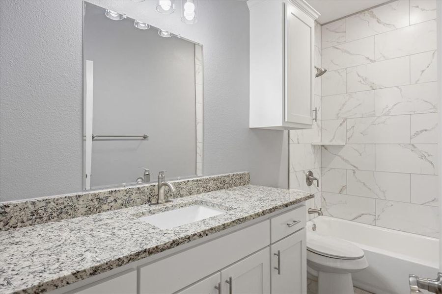 Secondary full bathroom featuring vanity, toilet, and tiled shower / bath combo