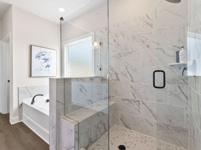 The primary bathroom boasts a luxury tub and modern walk-in shower.