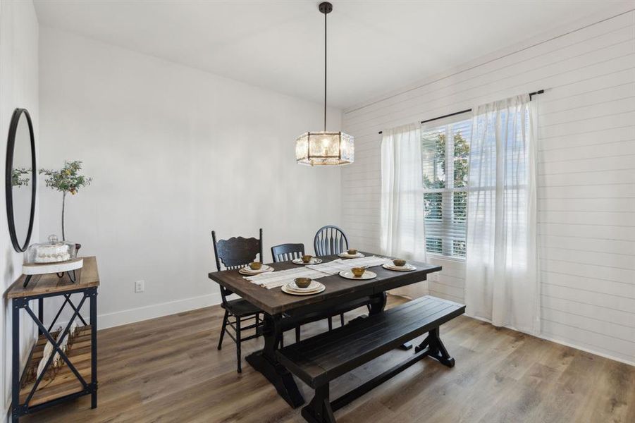 Dining area featuring wood-finish flooring, a contemporary ceiling fixture, and a window with blinds