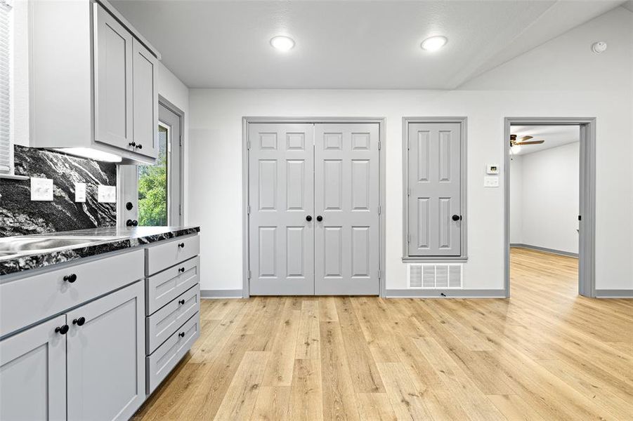 Kitchen with light wood-type flooring, dark stone countertops, and a ceiling fan Kitchen with light wood-type flooring, dark stone countertops, and a ceiling fan