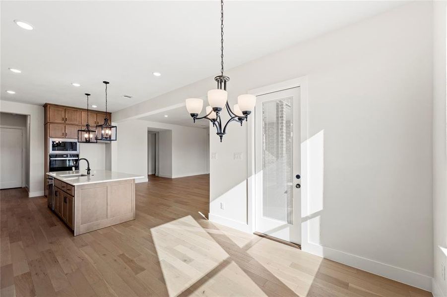 Kitchen featuring pendant lighting, sink, a kitchen island with sink, a notable chandelier, and built in microwave