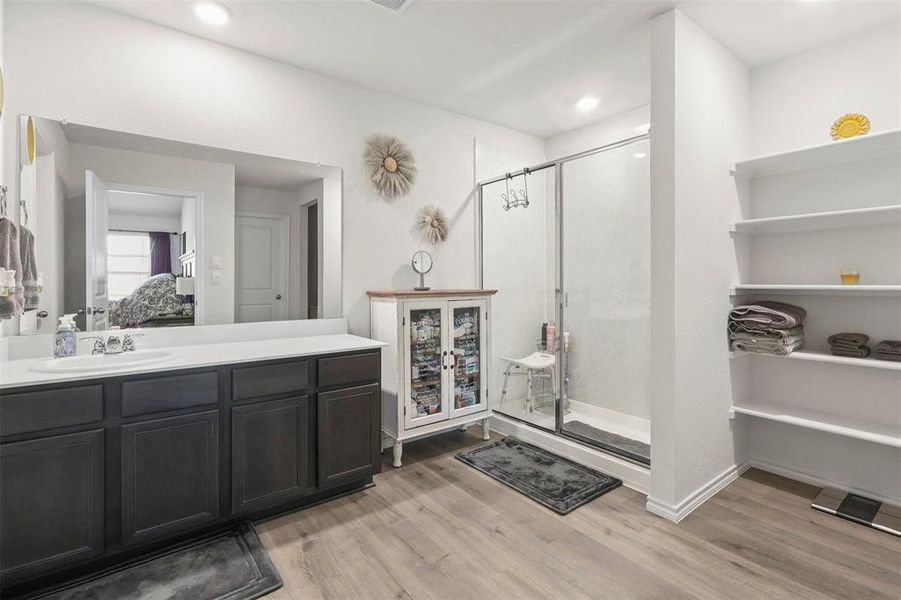 Bathroom featuring light wood-style floors, vanity, a stall shower, and ensuite bath