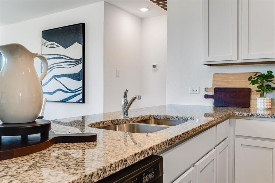 Kitchen featuring sink, white cabinetry, and light stone countertops