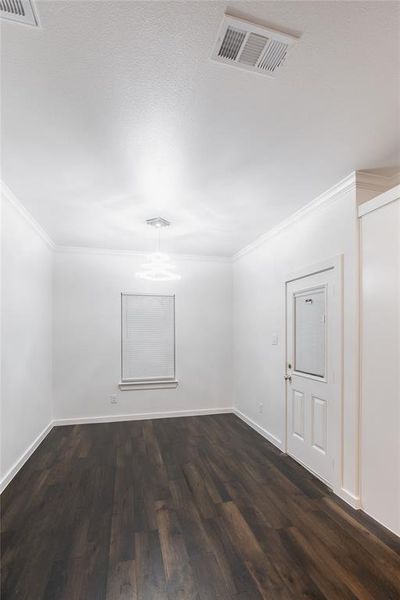Spare room featuring dark wood-style floors, visible vents, crown molding, and baseboards Spare room featuring dark wood-style floors, visible vents, crown molding, and baseboards