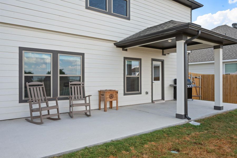 An inviting covered concrete patio provides sheltered outdoor living space adjacent to the grassy lawn. An inviting covered concrete patio provides sheltered outdoor living space adjacent to the grassy lawn.
