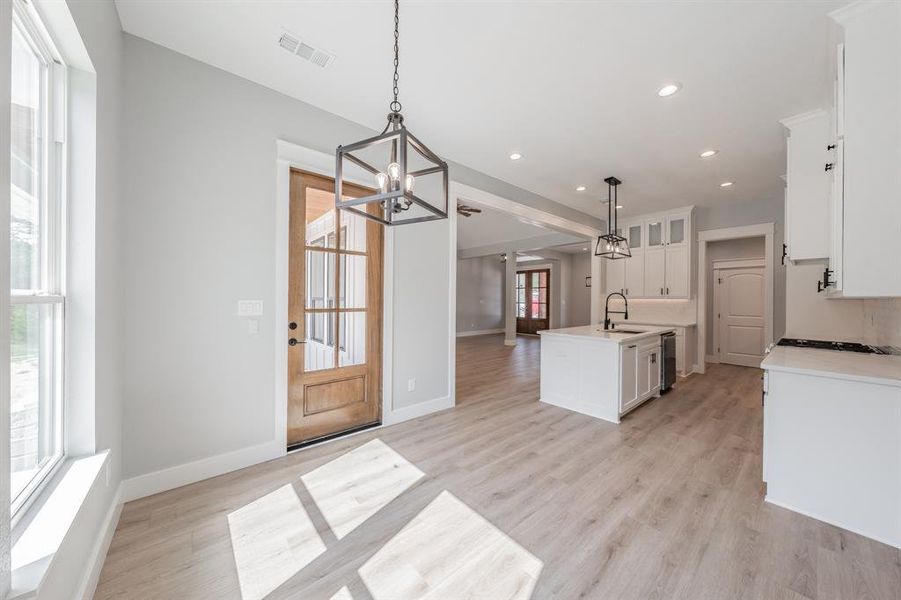 Kitchen with a wealth of natural light, a center island with sink, pendant lighting, and light hardwood / wood-style floors