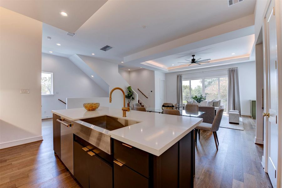 Large island featuring quartz countertops and gold hardware, complemented by a stainless steel deep sink.