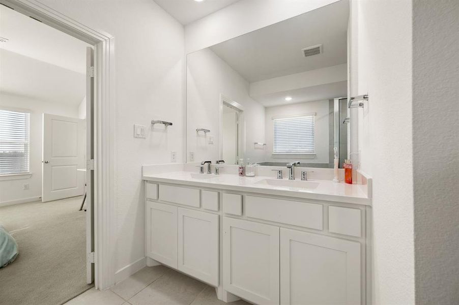 Full bath featuring light carpet, double vanity, and light tile patterned flooring