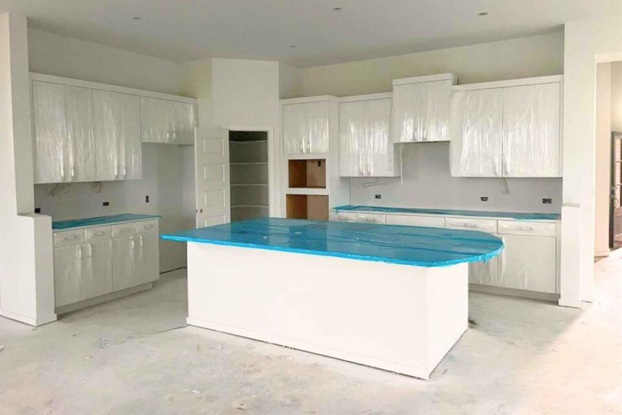 Kitchen with a kitchen island, concrete flooring, and white cabinets