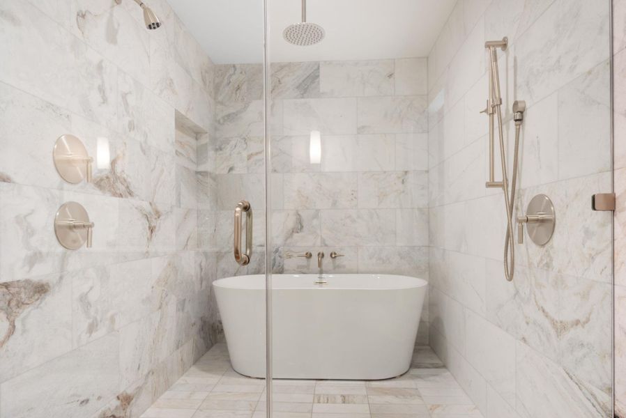 Full bathroom featuring tile walls, a freestanding tub, and a marble finish shower