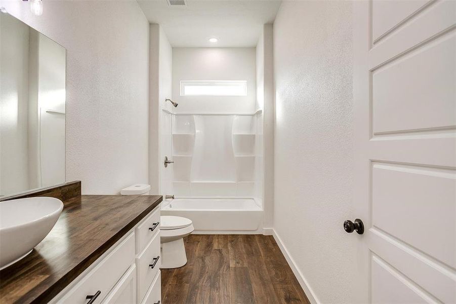 Full bathroom featuring toilet, washtub / shower combination, wood-type flooring, and vanity