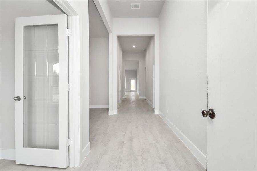 The majestic entryway allures with its high ceilings, embellished with sophisticated wood-look tile flooring and sleek oversized baseboards. Sample photo of completed home. Actual colors and selections will vary.