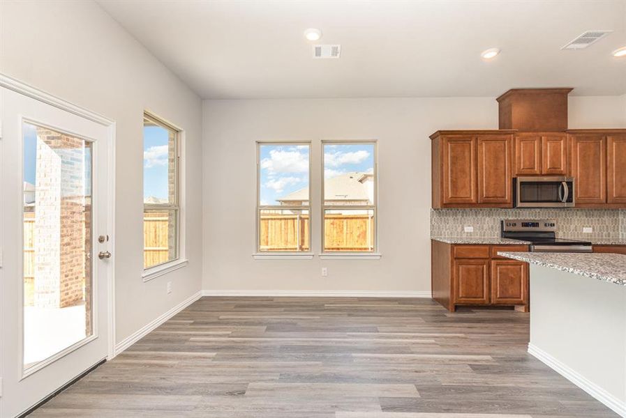 Kitchen with visible vents, brown cabinetry, light wood-style flooring, and appliances with stainless steel finishes