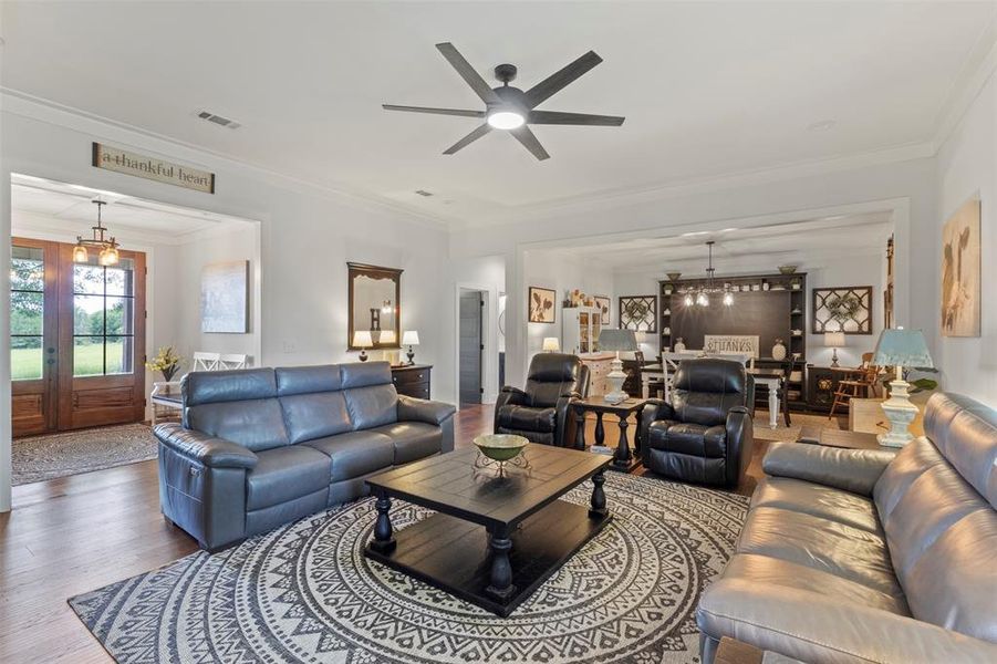Inviting living room featuring custom built-ins, a stone fireplace with wood mantel, hardwood floors, and abundant natural light, creating a warm and comfortable gathering space.