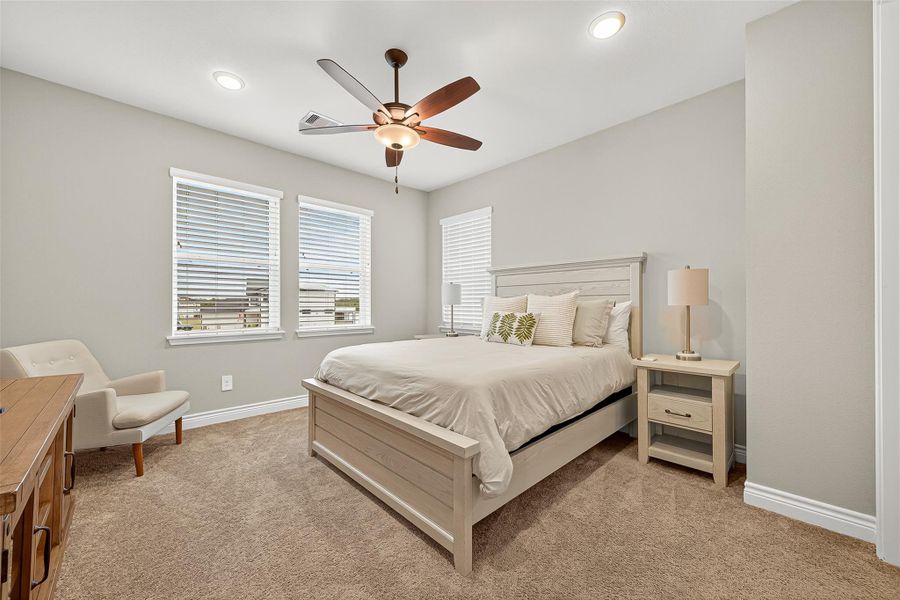 Private guest suite with soft neutral finishes, ceiling fan, and large windows offering natural light and a view toward the lake. Private guest suite with soft neutral finishes, ceiling fan, and large windows offering natural light and a view toward the lake.