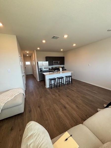 Open-concept living space with wood-finish flooring, recessed lighting, and a kitchen island featuring a light-toned countertop