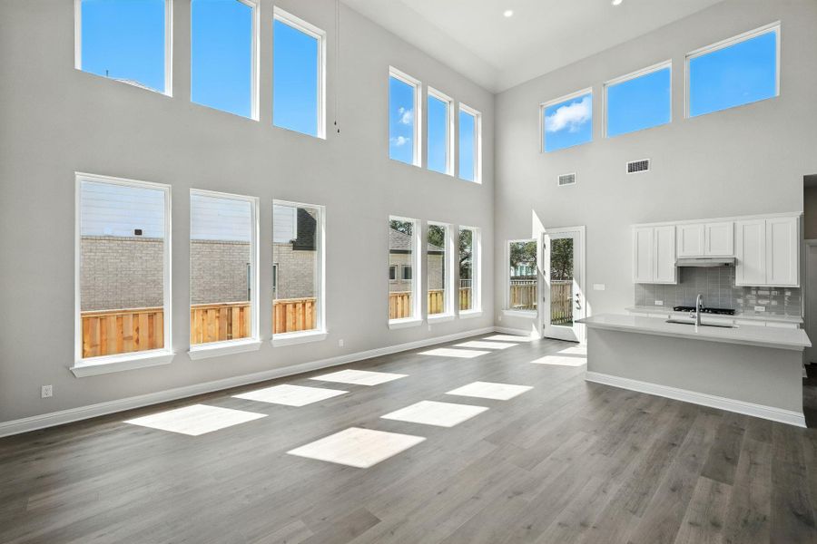 Unfurnished living room featuring a towering ceiling, dark wood-style floors, and plenty of natural light Unfurnished living room featuring a towering ceiling, dark wood-style floors, and plenty of natural light