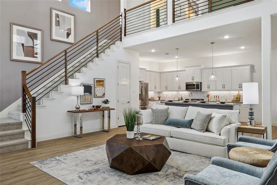 Spacious open-concept living area featuring wood-finish flooring and a contemporary staircase with wood and metal railings