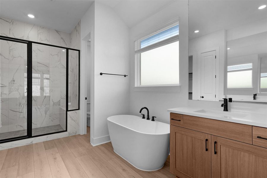 Bathroom featuring a marble finish shower, vanity, a freestanding tub, recessed lighting, and light wood-style floors