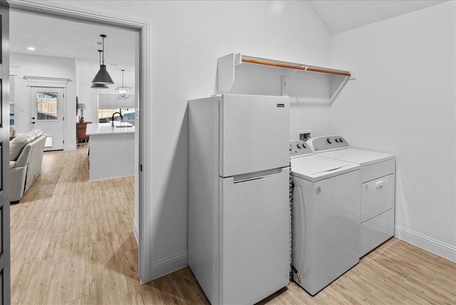 Clothes washing area with baseboards, light wood-type flooring, laundry area, independent washer and dryer, and a sink