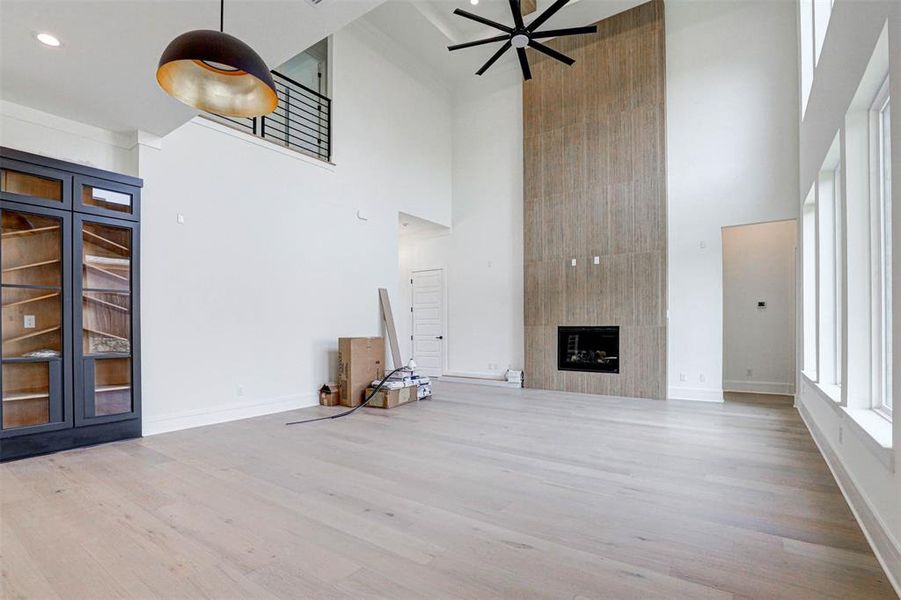 Unfurnished living room featuring a high ceiling, a fireplace, and wood-type flooring