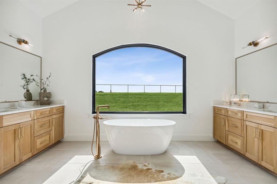 Primary bathroom featuring a soaking tub, vaulted ceiling, and dual vanities