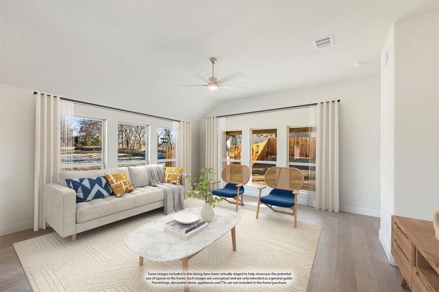 Living room with vaulted ceiling, ceiling fan, large windows, gray sofa, and hardwood floors