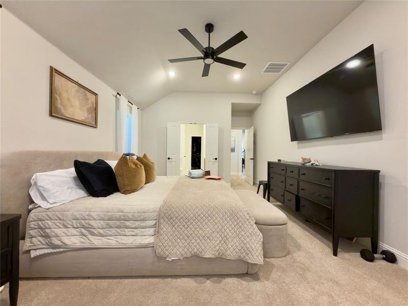 Bedroom with light carpet, ceiling fan, vaulted ceiling, and recessed lighting