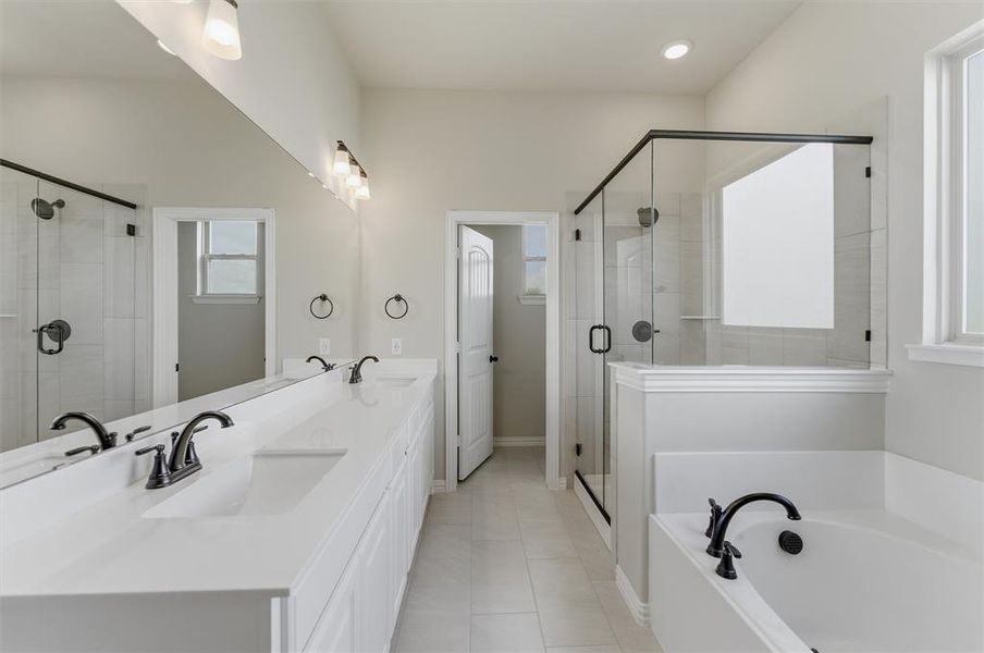 Full bath featuring double vanity, a shower stall, a garden tub, and light tile patterned flooring Full bath featuring double vanity, a shower stall, a garden tub, and light tile patterned flooring
