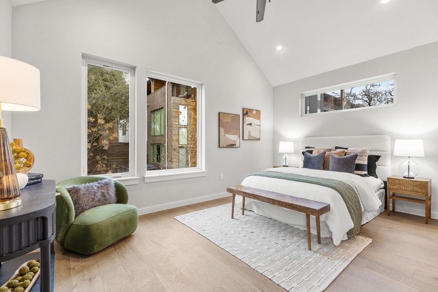 Bedroom featuring high vaulted ceiling, multiple windows, and light wood-type flooring