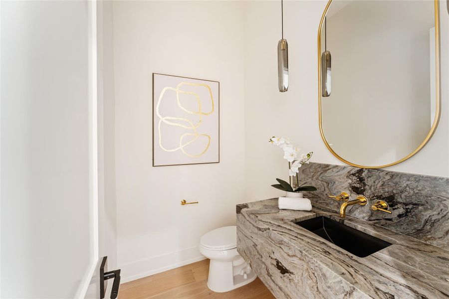 Exquisite powder room features striking smoke glass pendant lights that create a sophisticated ambiance.  Combining modern elegance with thoughtful design details will make your guests feel pampered.