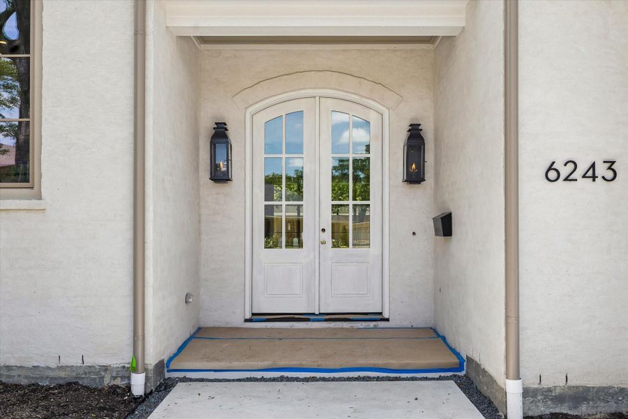A closer view of the entry with a custom front door and gas lanterns. The front door will be finished in a warm green color, Paris Rain by Benjamin Moore. Landscaping to be completed the week of May 25th.