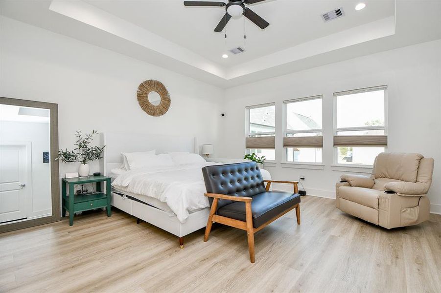 The primary bedroom upstairs has ample natural light from multiple windows and a ceiling fan.