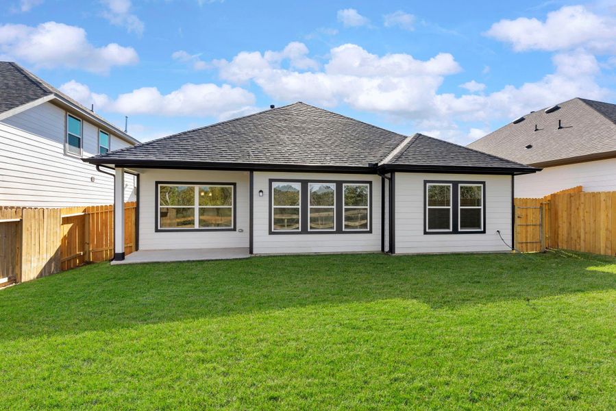 This home’s rear view offers abundant natural light through large windows and a roomy fenced backyard.