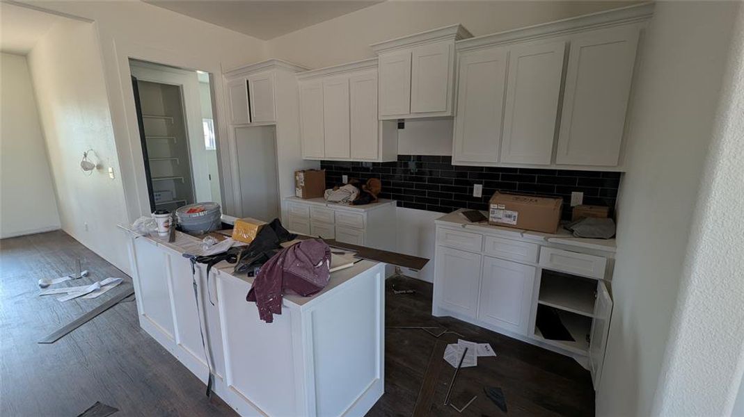 Kitchen featuring dark wood finished floors, white cabinets, and tasteful backsplash