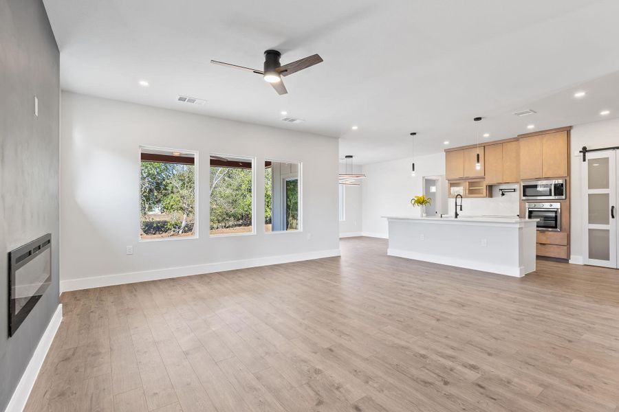 Unfurnished living room with a barn door, a ceiling fan, recessed lighting, and light wood-type flooring