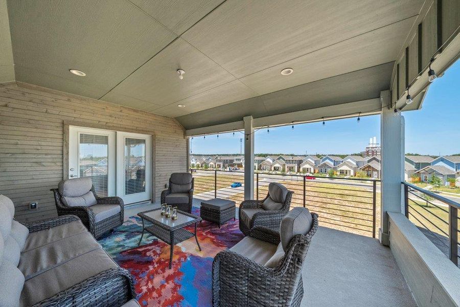 An elevated, covered balcony overlooks a neighborhood setting with glass-paneled access doors. An elevated, covered balcony overlooks a neighborhood setting with glass-paneled access doors.