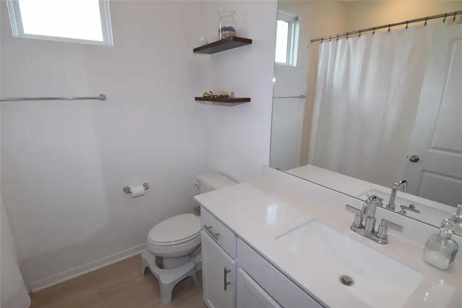 Clean lines and a stone vanity top define this light-filled modern bathroom space.