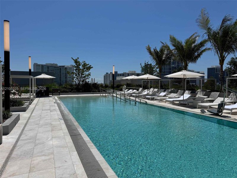 Expansive outdoor pool with integrated lighting and surrounding lounge chairs under umbrellas