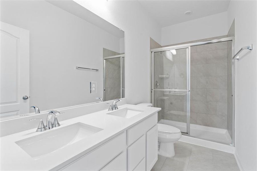 This primary bathroom features an oversized walk-in shower with tile surround, stained cabinets with light countertops and dual vanities, high ceilings, custom paint, sleek and dark modern finishes.