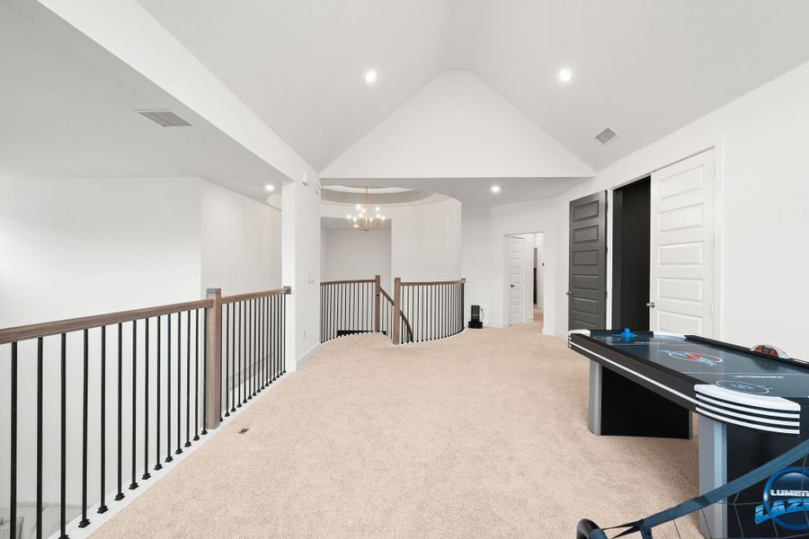 A spacious upper-level living area offers vaulted ceilings and soft carpeting, ideal for a flexible recreational space.