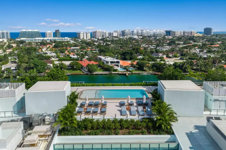 Rooftop swimming pool with paved decking and integrated landscaping, featuring a backdrop of coastal and urban scenery Rooftop swimming pool with paved decking and integrated landscaping, featuring a backdrop of coastal and urban scenery