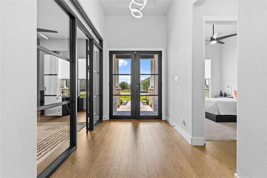 Entryway featuring a ceiling fan, wood finished floors, a textured wall, and french doors