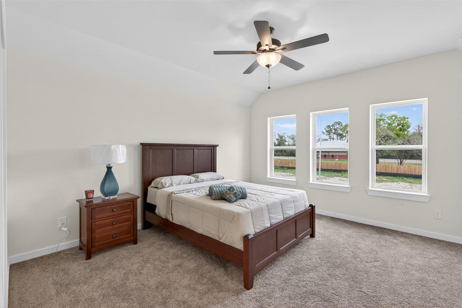 Expansive primary suite featuring vaulted ceilings, plush carpeting, and abundant natural light, creating a serene and elevated retreat. Expansive primary suite featuring vaulted ceilings, plush carpeting, and abundant natural light, creating a serene and elevated retreat.