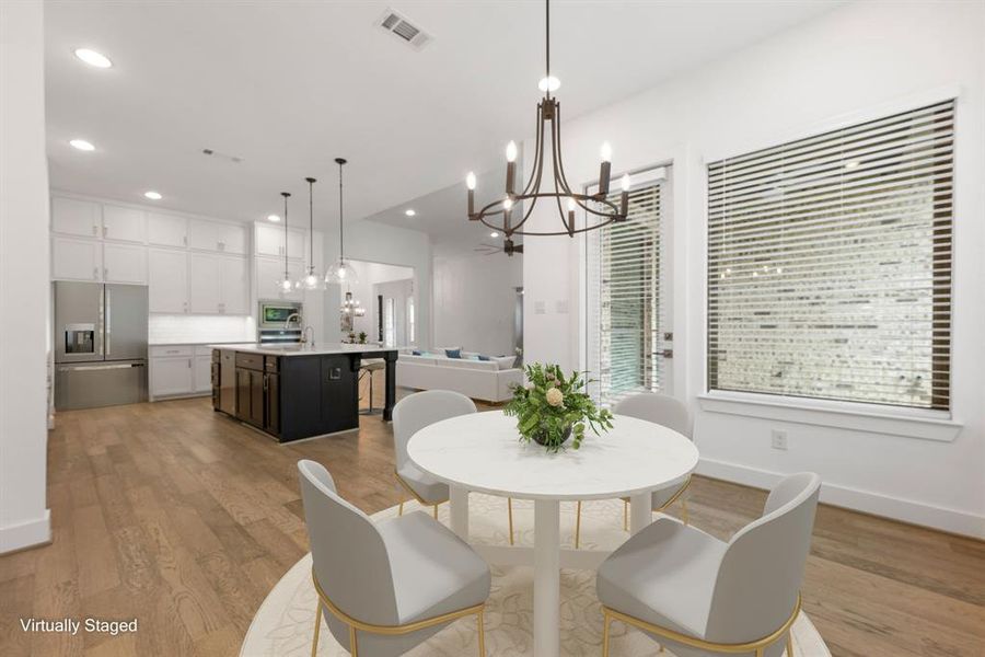 This lovely breakfast area is perfect for starting the day out on the right foot.  This space showcases high ceilings, custom chandelier light, recessed lighting, large window adding to the ample natural light in the kitchen, with rich engineered wood floors and access to the outdoor entertainment.