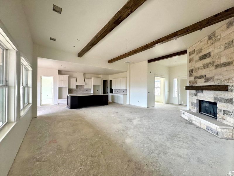 Exposed beams and a stone fireplace define the character of this expansive open-concept space.