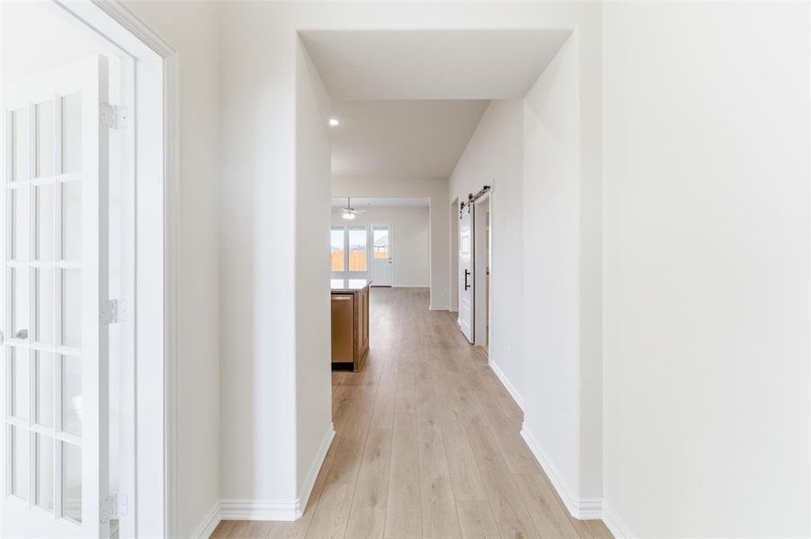 Hallway featuring a barn door and light wood-type flooring Hallway featuring a barn door and light wood-type flooring